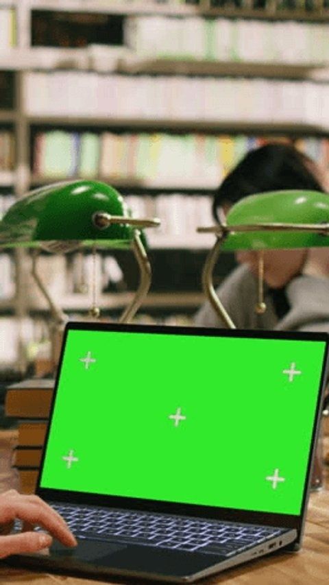 Laptop med grön redigeringsskärm framför två gröna skrivbordslampor