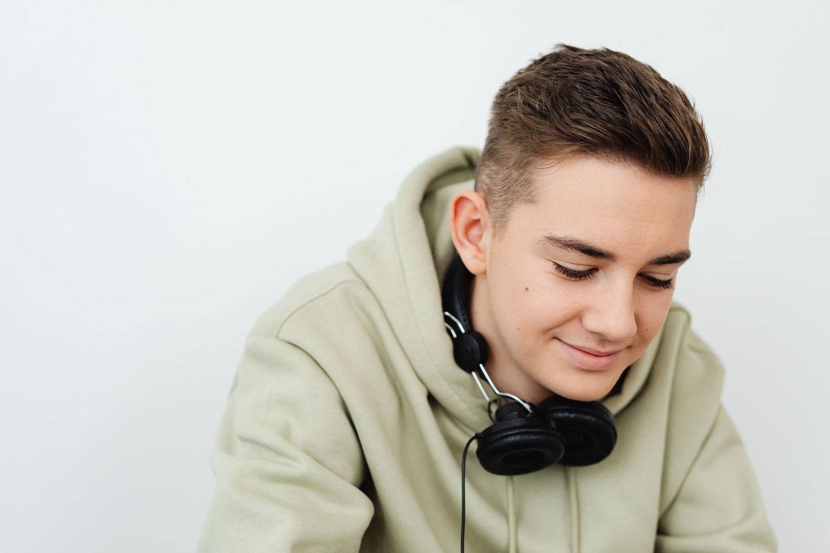 Ung person i ljus hoodie med svarta hörlurar runt halsen
